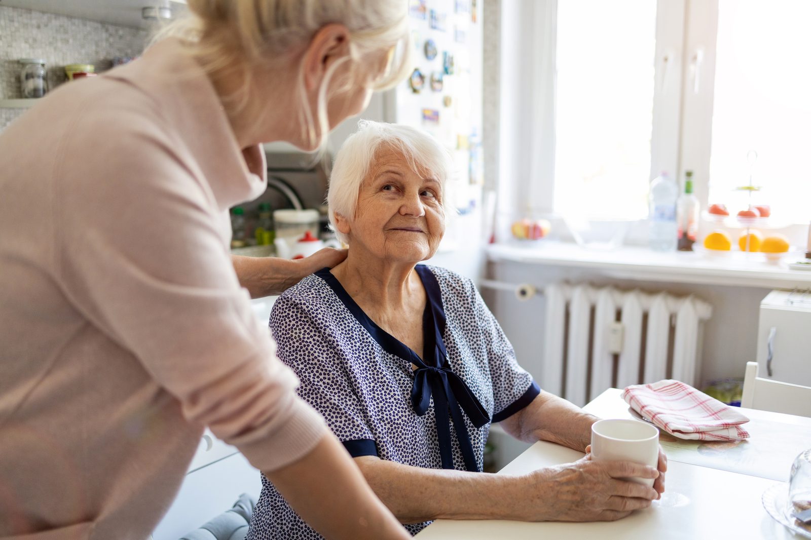 Betreuungskraft und Seniorin am Küchentisch