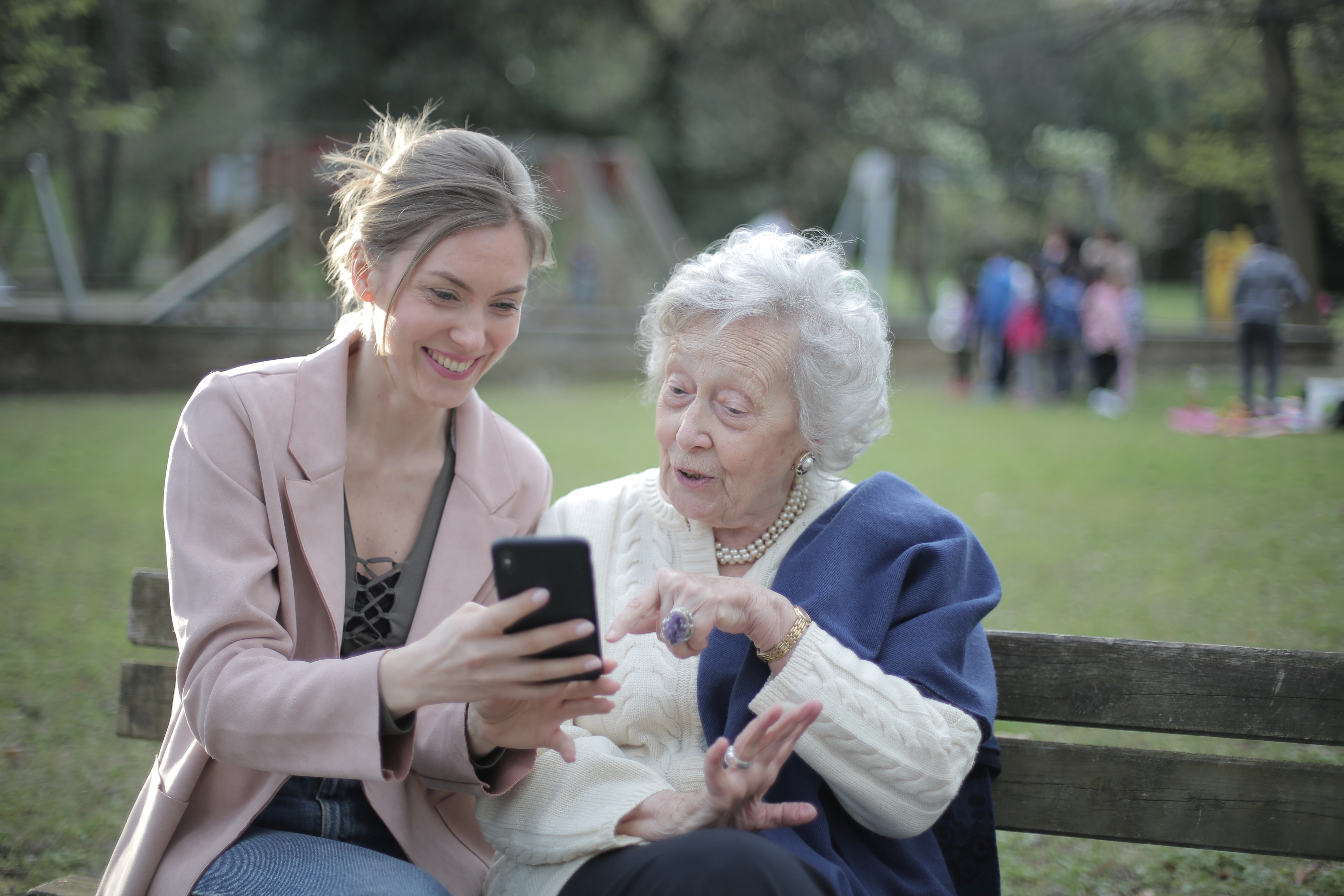 Junge Frau und Seniorin schauen gemeinsam auf ein Smartphone