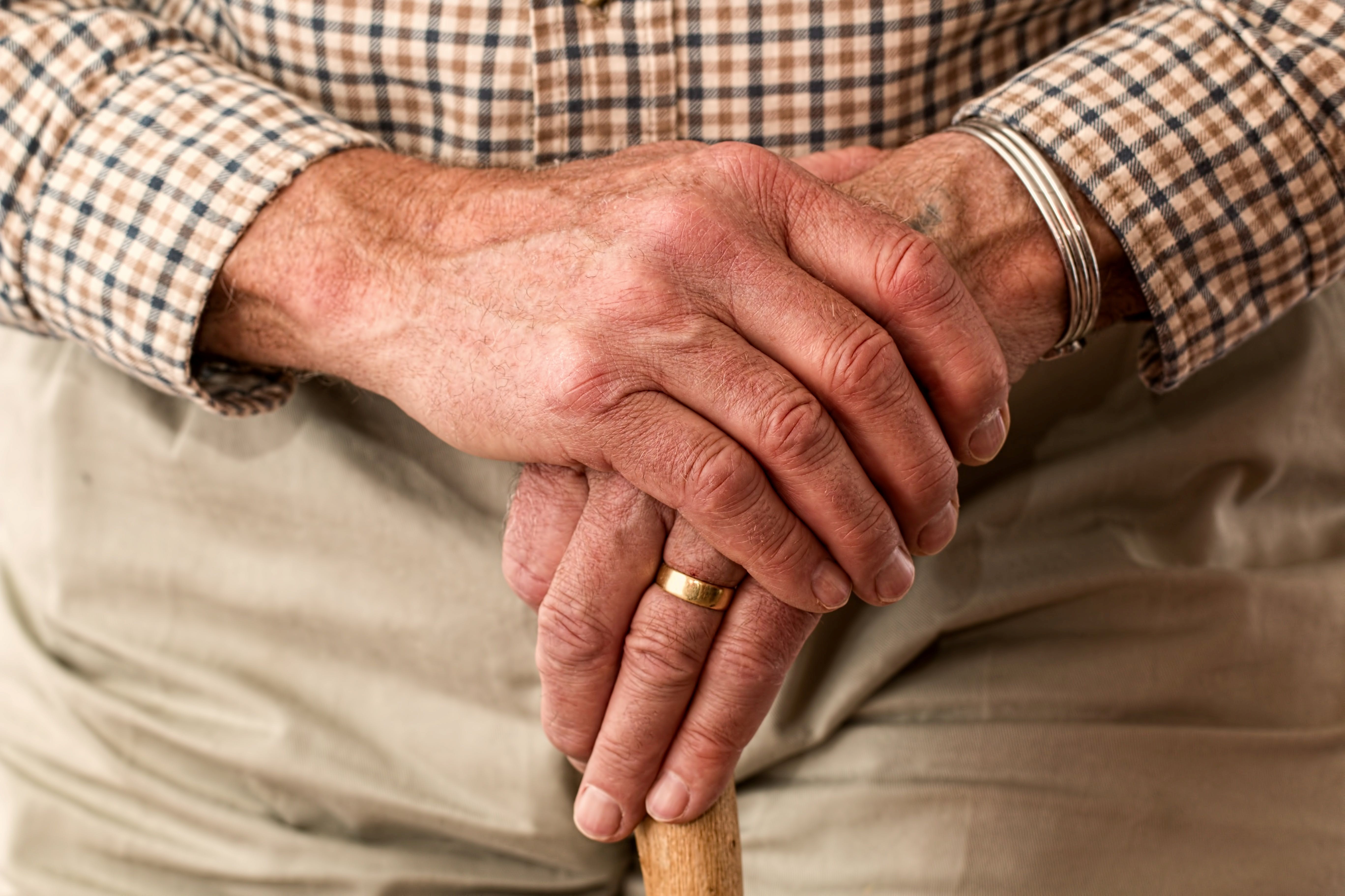 Hände eines Seniors ruhen auf einem Gehstock